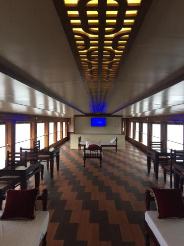 a large room with tables and chairs and a television at Beach Paradise Day Cruise Houseboat in Alleppey