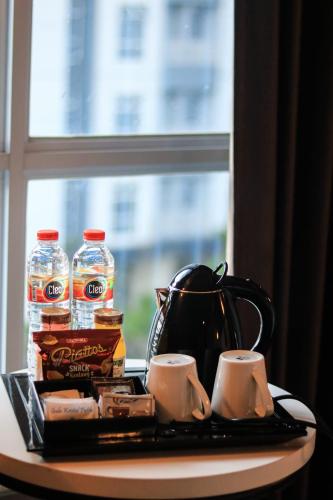 a tray with a tea kettle and cups on a table at BeSS Mansion Hotel Surabaya in Wonocolo