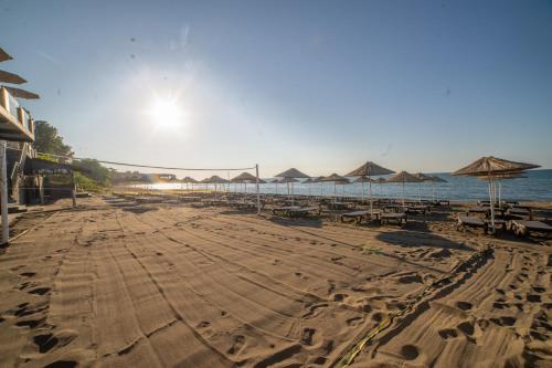 a sandy beach with umbrellas and tables and the ocean at Atik Hotel in Unye