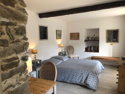 a bedroom with a bed and a stone wall at Le Balcon Commingeois in Chein-Dessus