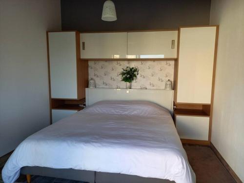 a bedroom with a white bed with a headboard at Lac Grand Lieu : maisonnette au calme avec jardin in Saint-Lumine-de-Coutais