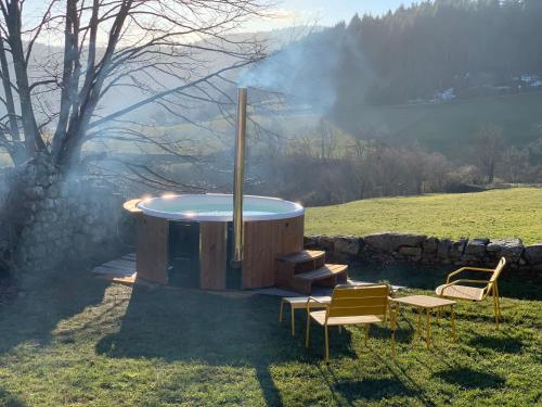 a hot tub in a field with a group of chairs at CASARIOU Les Bernards Villa Grande bâtisse 12p avec cheminée bain nordique billiard piscine in Vaudevant