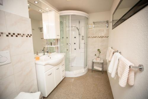 baño blanco con ducha y lavamanos en Pension Knoll, en Schörfling am Attersee