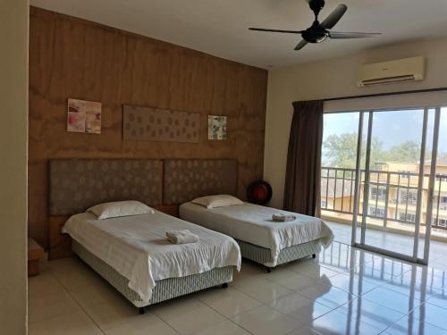 two beds in a hotel room with a balcony at Gold Coast Morib Resort in Banting