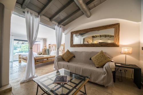 a living room with a couch and a mirror at Hôtel Le Roi Théodore & Spa in Porto-Vecchio