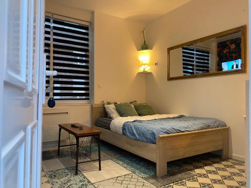 une chambre avec un lit et un miroir dans l'établissement Le petit studio à découvrir..., à Marquette-lès-Lille