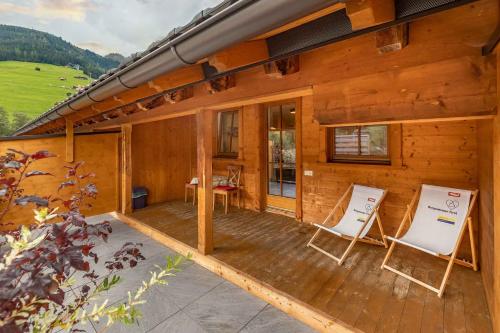 a wooden cabin with two chairs on a deck at Aparthotel Hummerau in Alpbach