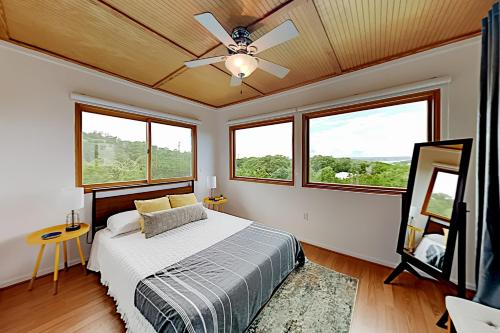 um quarto com uma cama, uma ventoinha de tecto e janelas em Cowboy Retreat em Canyon Lake