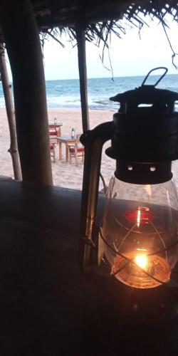 a candle in a glass jar on a table near the beach at The Alpha Monkey hotel & Tree house in Tangalle