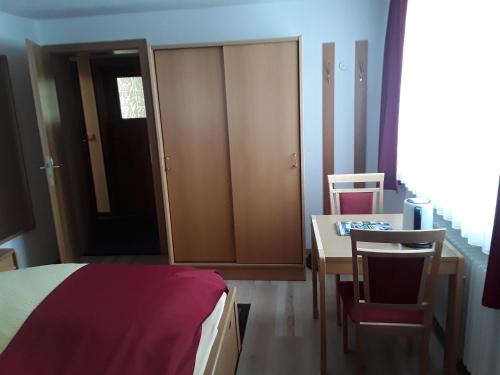 a bedroom with a bed and a table and a desk at Pension Waldeck Fleckl in Warmensteinach