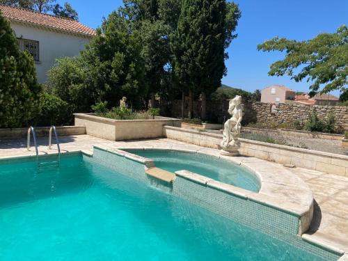 a swimming pool with a statue next to a house at Gîte Encore Un Soir in Hyères