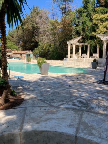 a swimming pool with a gazebo and a tree at Gîte Encore Un Soir in Hyères