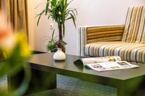 a coffee table with a couch and a vase on it at Hotel Mursalitsa by HMG - Half board in Pamporovo