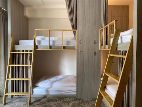 a room with three bunk beds with white sheets at We Come Hostel in Taipei
