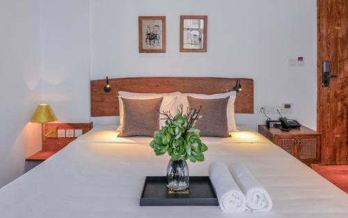 a bedroom with a bed with a vase with a plant at 22Land Hotel & Residence in Hanoi