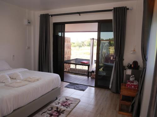 a bedroom with a bed and a sliding glass door at Nansilarom in Ban Bun Yun