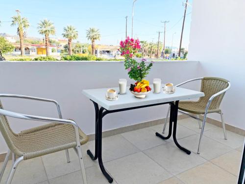 a white table with a bowl of fruit and flowers on it at Apollonio Suites & Rooms Faliraki Rhodes in Faliraki