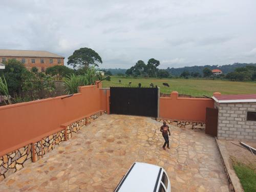 a man standing on a patio with a view of a field at Glen's Apartment in Entebbe