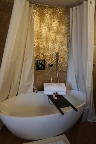 - une baignoire blanche avec rideau de douche et serviettes dans l'établissement Tonic Hotel Saint Germain des Prés, à Paris