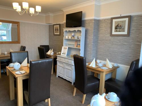 a waiting room with tables and chairs and a tv at Philmar Guest House in Skegness