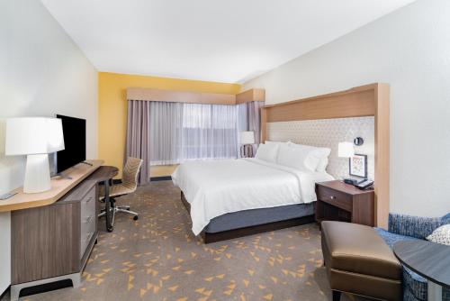 a hotel room with a bed and a desk with a computer at Holiday Inn Southaven Central - Memphis by IHG in Southaven