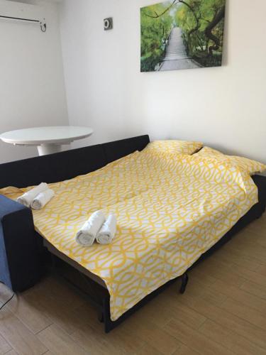 een bed in een kamer met twee witte schoenen erop bij Apartman Dorotea in Zaton