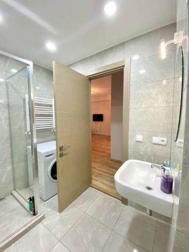 a bathroom with a sink and a washing machine at Sol's M2 White Modern Apartments in Tbilisi City