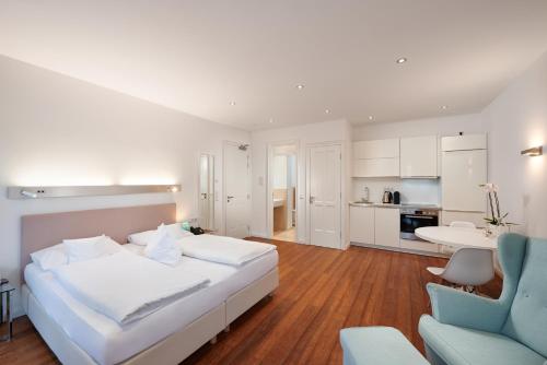 1 Schlafzimmer mit einem weißen Bett und einer Küche in der Unterkunft Deluxe Apartment 35qm im Design Hotel Vosteen in Nürnberg