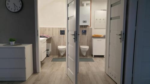 a bathroom with two toilets and a clock on the wall at Apartament STYL in Otmuchów