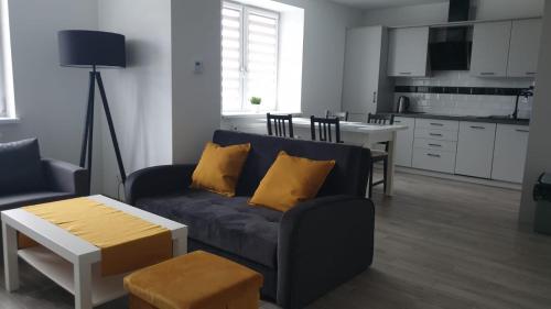 a living room with a couch and a table and a kitchen at Apartament STYL in Otmuchów