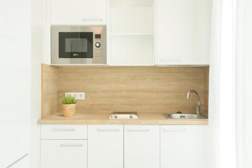 a white kitchen with a sink and a microwave at Bungalows Doña Rosa in Playa del Ingles