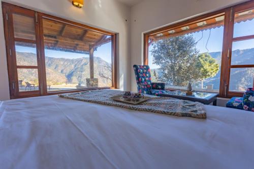 a bedroom with a large bed and large windows at Seclude Ramgarh Willows in Rāmgarh