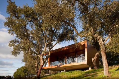 a house on a hill with trees in the foreground at Herdade do Moinho Novo in Canha