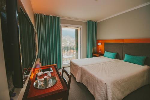 a hotel room with a bed and a window at Solar da Bica in São Vicente