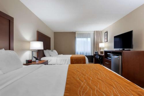 a hotel room with two beds and a flat screen tv at Comfort Inn Binghamton I-81 in Binghamton