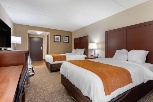 a hotel room with two beds and a flat screen tv at Comfort Inn Binghamton I-81 in Binghamton