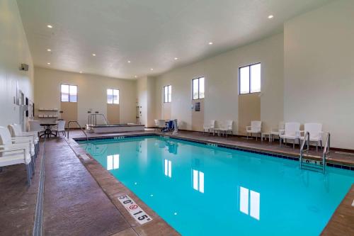 a large swimming pool with white chairs and a table at Comfort Inn & Suites Mandan - Bismarck in Mandan