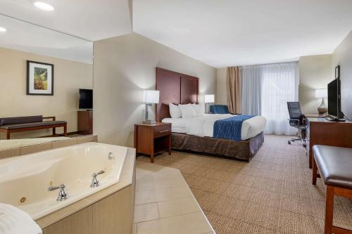 a hotel room with a bed and a bath tub at Comfort Inn & Suites Northern Kentucky in Wilder