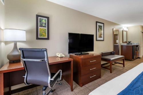 a hotel room with a desk with a television and a chair at Comfort Inn & Suites Northern Kentucky in Wilder