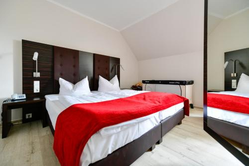 a bedroom with two beds and a red blanket at Landhotel Burg im Spreewald - Resort & Spa in Burg