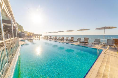 a swimming pool with chairs and umbrellas next to the ocean at Atik Hotel in Unye