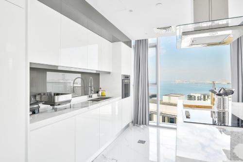 een witte keuken met uitzicht op de oceaan bij Luxurious 3 BR w maidroom in BLUEWATERS ISLAND in Dubai