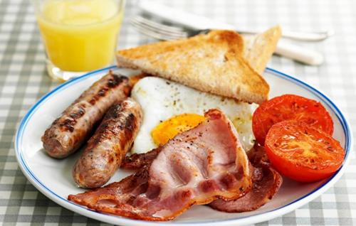 a plate of breakfast food with sausage eggs bacon and toast at Hinsley Hall in Leeds