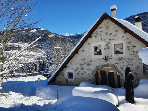 a building covered in snow with a mountain in the background at Le Valombré in Saint-Pierre-de-Chartreuse