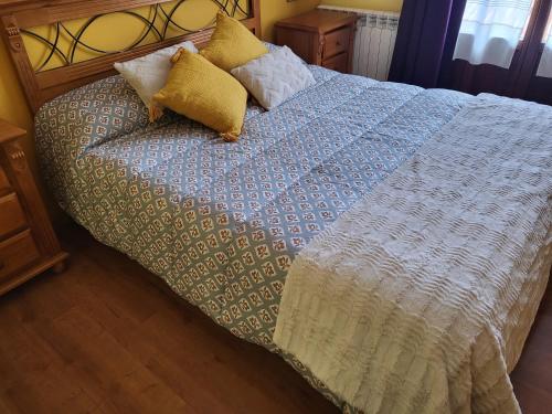 a bed with a blue and white blanket and pillows at Hotel Virginia R.H. in Vinuesa