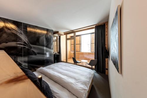 a bedroom with a bed and a large window at Hotel Arnica Scuol - Adults Only in Scuol