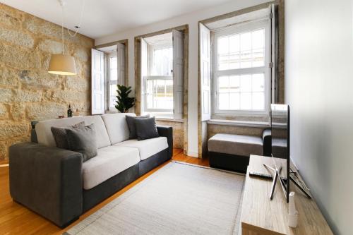 ein Wohnzimmer mit einem Sofa und 2 Fenstern in der Unterkunft MSC Flats - Comercio do Porto in Porto