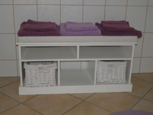 een witte plank met paarse handdoeken en manden bij Appartement Viersen in Fehmarn