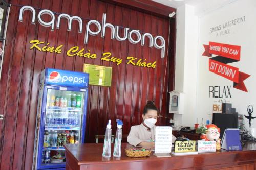a woman wearing a mask behind a counter in a store at Nam Phương Hotel Sa Đéc in Sa Ðéc
