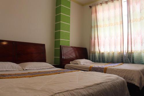 two beds in a room with green and white walls at Nam Phương Hotel Sa Đéc in Sa Ðéc